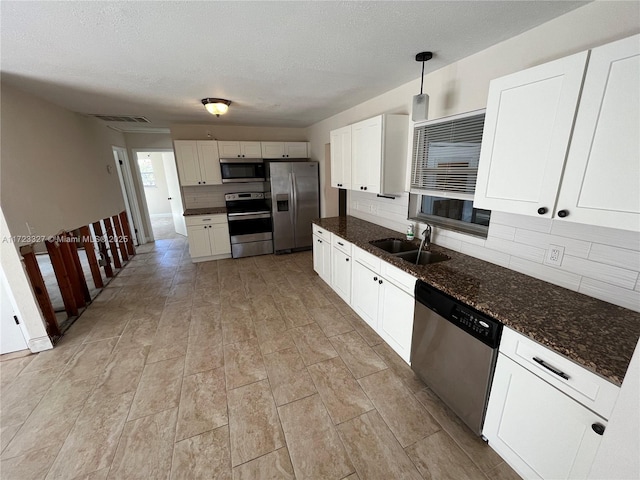 kitchen with sink, pendant lighting, decorative backsplash, white cabinets, and appliances with stainless steel finishes