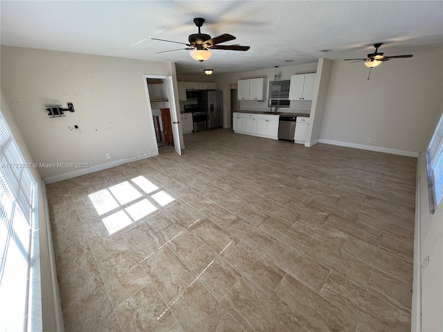 unfurnished living room featuring ceiling fan and sink