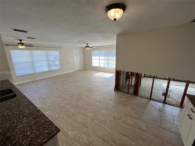 unfurnished living room with a textured ceiling, ceiling fan, and sink