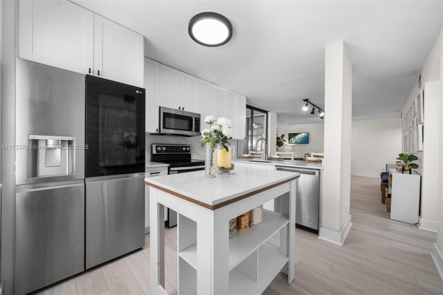 kitchen with light stone countertops, appliances with stainless steel finishes, sink, and white cabinets