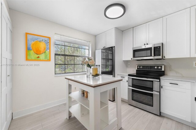 laundry area with stacked washer / drying machine and light hardwood / wood-style flooring