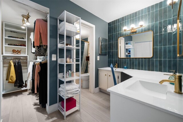 bathroom featuring hardwood / wood-style floors, vanity, and tile walls