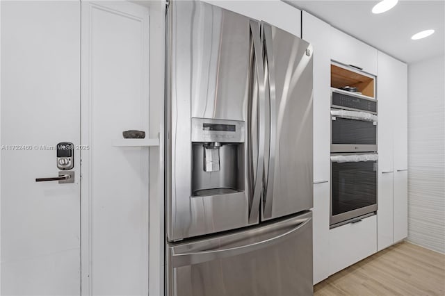 kitchen featuring white cabinetry, stainless steel appliances, and light wood-type flooring