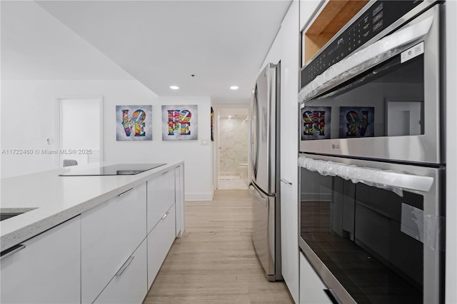 kitchen with white cabinets, appliances with stainless steel finishes, and light wood-type flooring