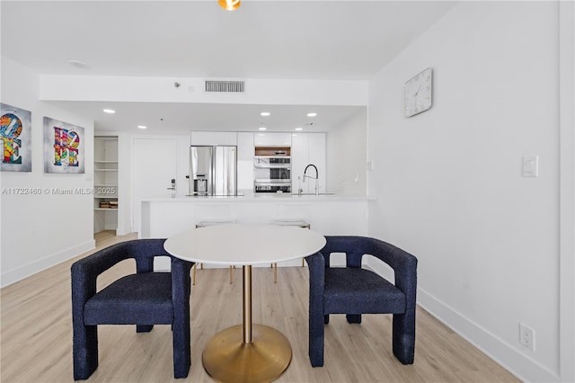 dining area with built in shelves, sink, and light hardwood / wood-style floors