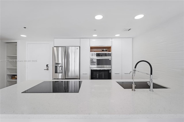 kitchen with white cabinets, light stone countertops, sink, and appliances with stainless steel finishes