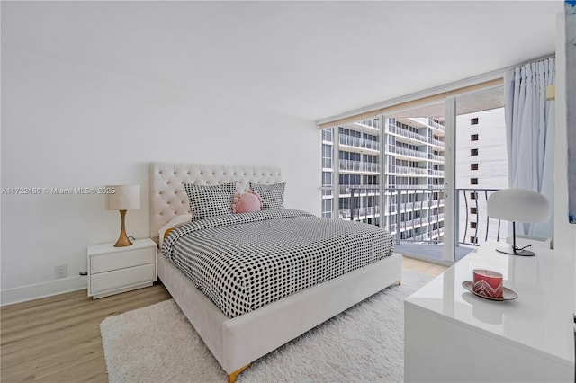 bedroom featuring expansive windows and light hardwood / wood-style flooring