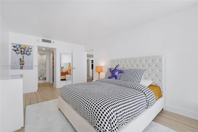 bedroom featuring ensuite bathroom and light hardwood / wood-style floors