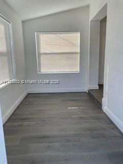 unfurnished room featuring dark hardwood / wood-style floors and vaulted ceiling