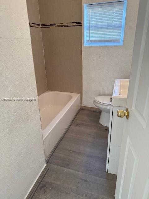 1545 NW 68st, Miami, FL 33147 - full bath featuring a textured wall, toilet, baseboards, and wood finished floors