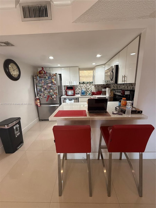 8290 Lake Dr Unit 235, Doral, FL 33166 - kitchen with stainless steel appliances, a peninsula, white cabinets, a breakfast bar, and recessed lighting