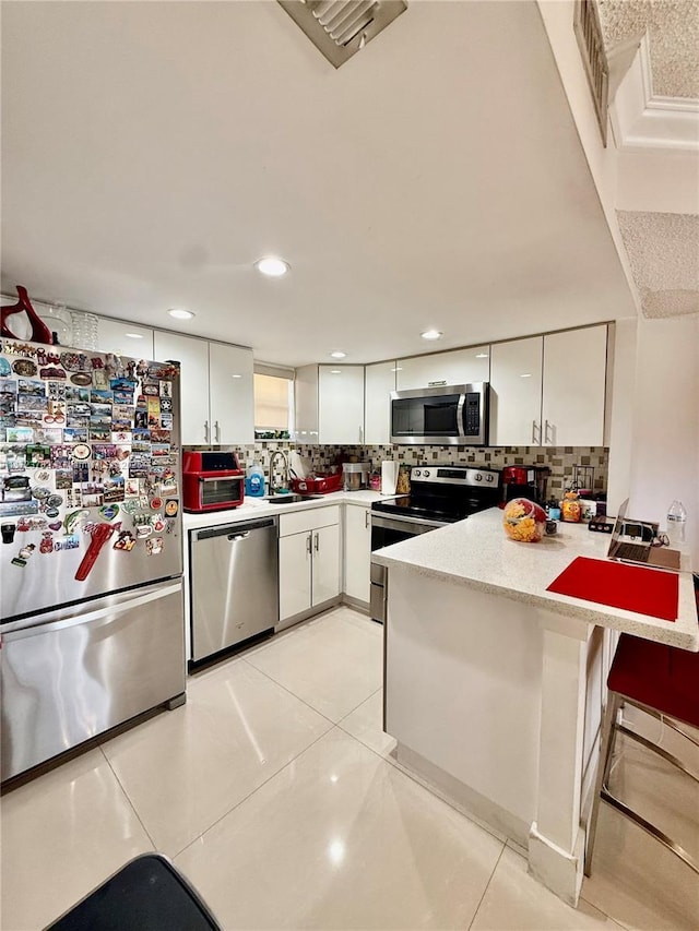 8290 Lake Dr Unit 235, Doral, FL 33166 - kitchen with appliances with stainless steel finishes, a peninsula, a sink, white cabinets, and tasteful backsplash