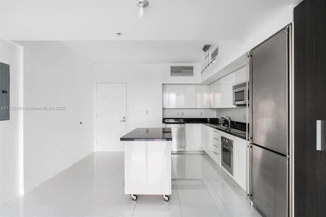 kitchen with a center island, sink, white cabinetry, stainless steel appliances, and light tile patterned floors