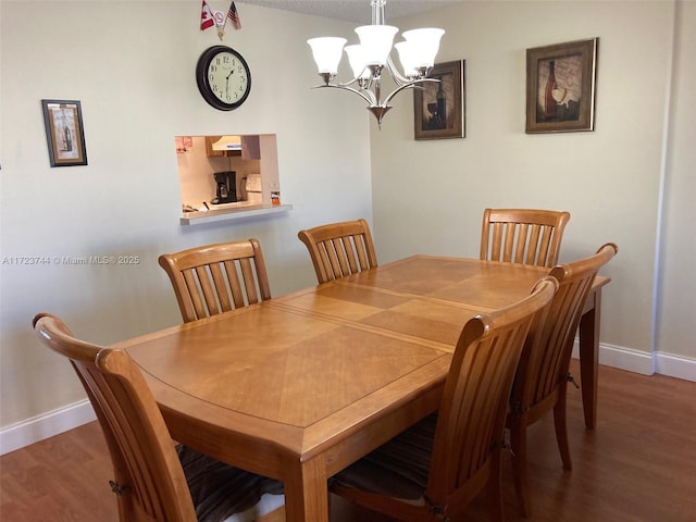 dining space with wood-type flooring and an inviting chandelier