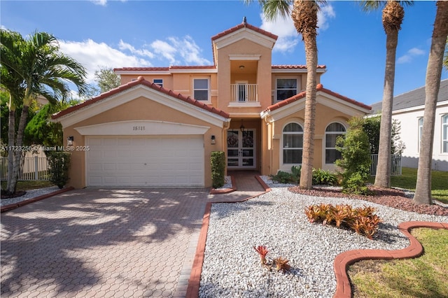 mediterranean / spanish-style home with french doors, a balcony, and a garage