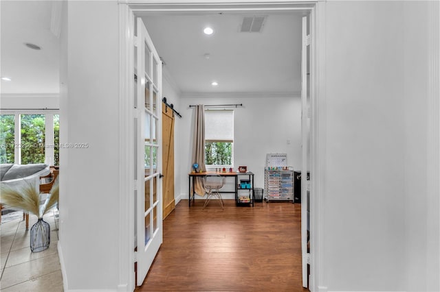 hallway featuring a barn door, crown molding, french doors, and dark wood-type flooring