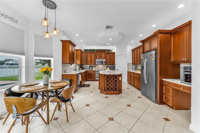 kitchen with decorative backsplash, stainless steel appliances, sink, a center island, and hanging light fixtures