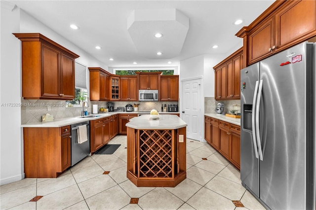 kitchen with sink, decorative backsplash, light tile patterned floors, appliances with stainless steel finishes, and a kitchen island