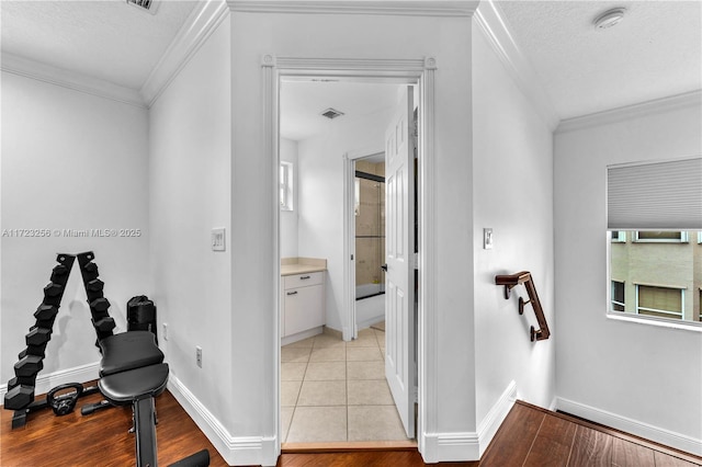 corridor with crown molding, light tile patterned flooring, and a textured ceiling