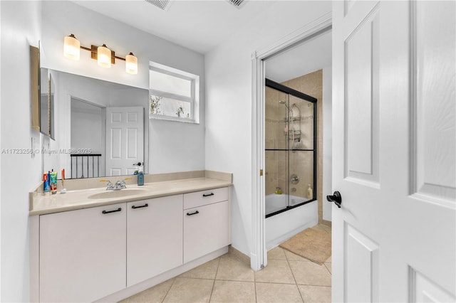 bathroom featuring tile patterned flooring, vanity, and bath / shower combo with glass door