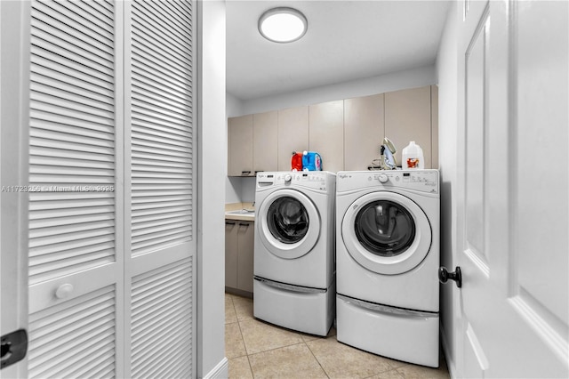 washroom with cabinets, light tile patterned floors, and washing machine and clothes dryer