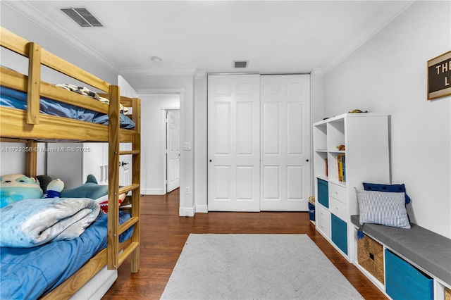 bedroom with dark wood-type flooring, crown molding, and a closet