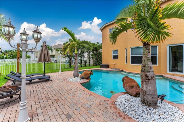 view of pool with a fire pit, a patio area, and a lawn