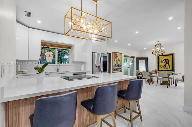 kitchen with white cabinets, stainless steel refrigerator with ice dispenser, decorative light fixtures, and a kitchen breakfast bar