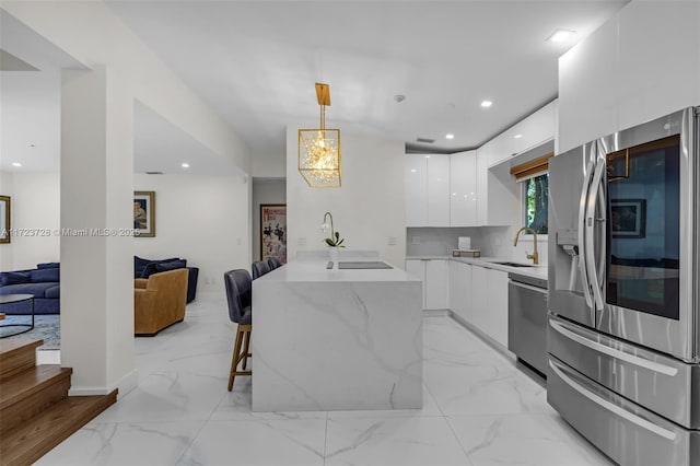 kitchen featuring pendant lighting, white cabinets, a kitchen breakfast bar, decorative backsplash, and stainless steel appliances