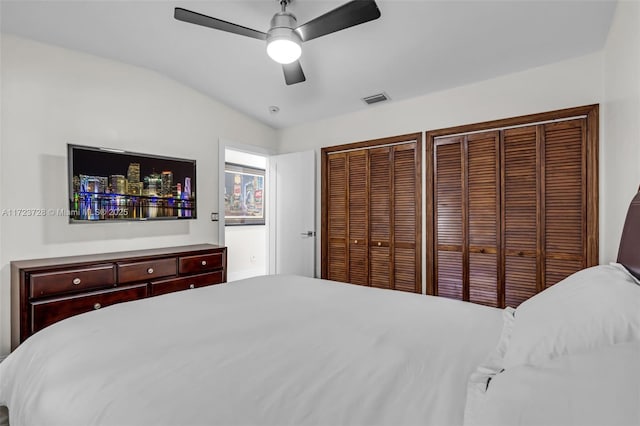 bedroom featuring two closets, vaulted ceiling, and ceiling fan