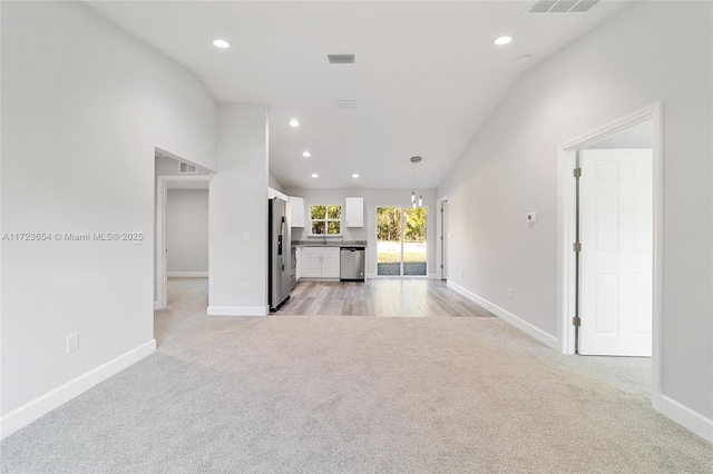 unfurnished living room with light carpet and vaulted ceiling