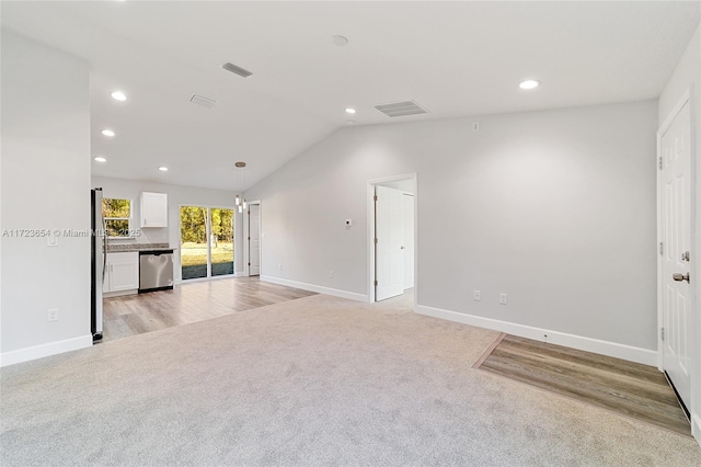 unfurnished living room with light colored carpet and lofted ceiling