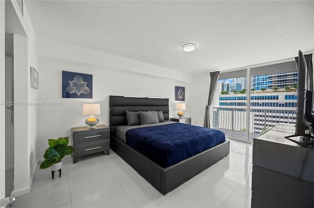 tiled bedroom with a textured ceiling, access to outside, and a wall of windows