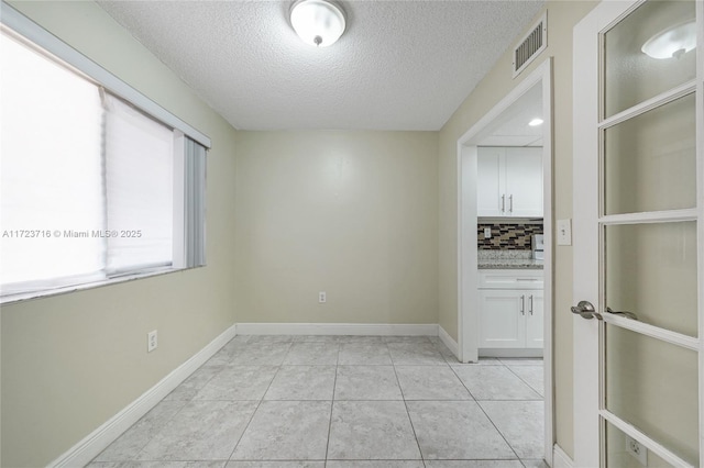 unfurnished room with light tile patterned floors and a textured ceiling