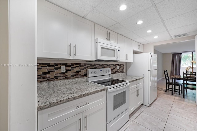 kitchen featuring a drop ceiling, light tile patterned floors, white appliances, decorative backsplash, and white cabinets