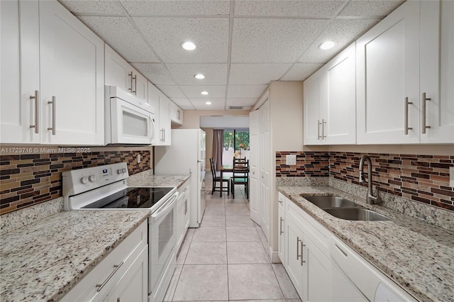 kitchen featuring a paneled ceiling, white cabinetry, white appliances, and sink