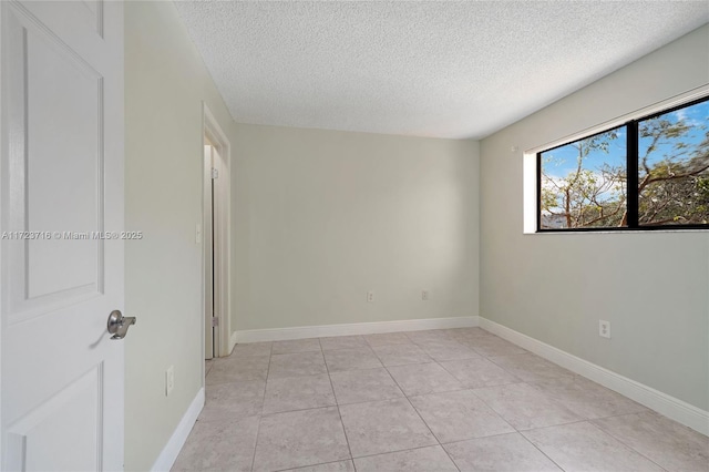 tiled empty room featuring a textured ceiling