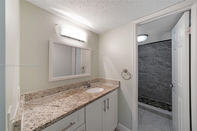 bathroom featuring a tile shower, tile patterned flooring, vanity, and a textured ceiling