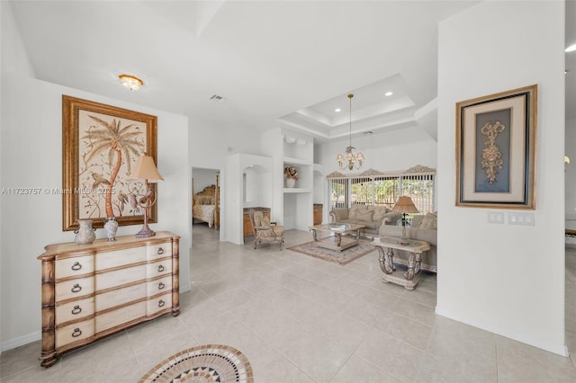 living room featuring light tile patterned flooring, a raised ceiling, and a chandelier