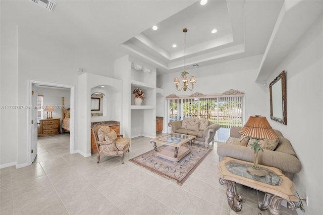 tiled living room featuring built in shelves, a raised ceiling, a high ceiling, and an inviting chandelier