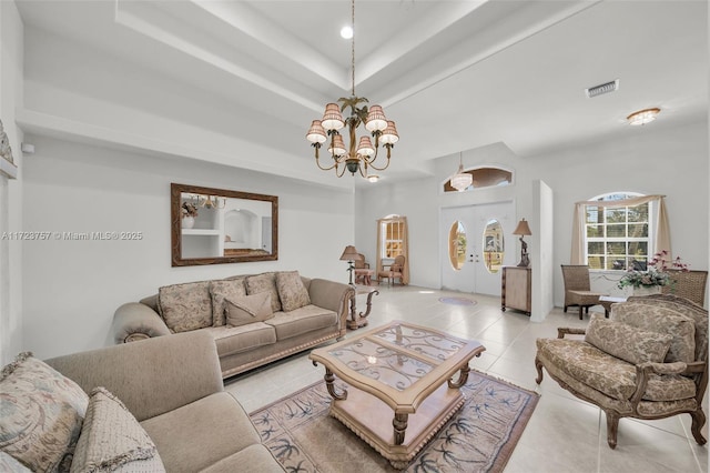 living room featuring a chandelier, french doors, light tile patterned floors, and a raised ceiling