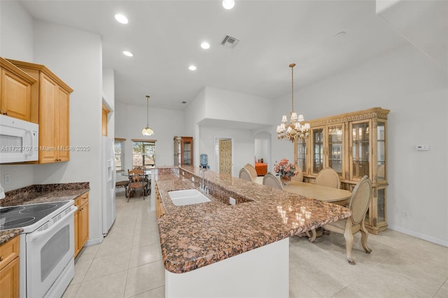 kitchen with a large island, a high ceiling, decorative light fixtures, and white appliances