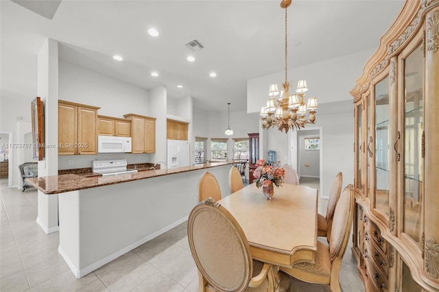 dining space with a towering ceiling, light tile patterned floors, and a notable chandelier