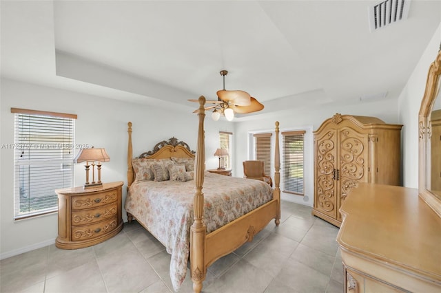 bedroom featuring ceiling fan, a raised ceiling, and multiple windows