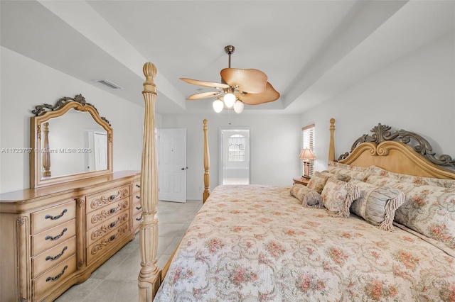 bedroom with a raised ceiling, ceiling fan, and light tile patterned flooring