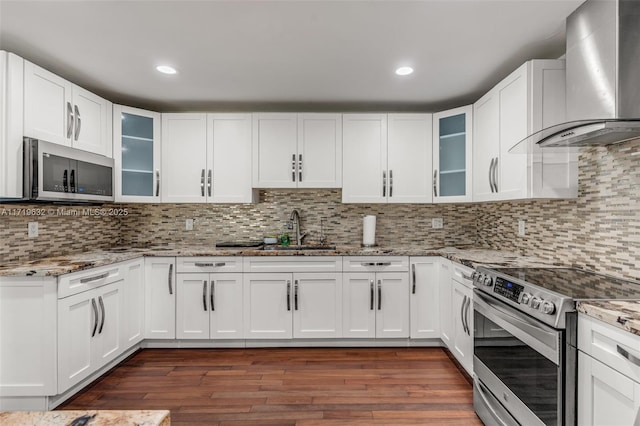 kitchen with stainless steel appliances, wall chimney exhaust hood, white cabinets, and sink