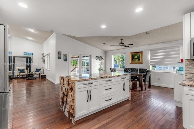 kitchen featuring ceiling fan, white cabinetry, lofted ceiling, and light stone countertops