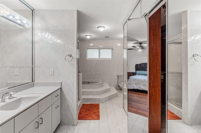 bathroom featuring tile walls, tile patterned floors, ceiling fan, a shower with shower door, and vanity