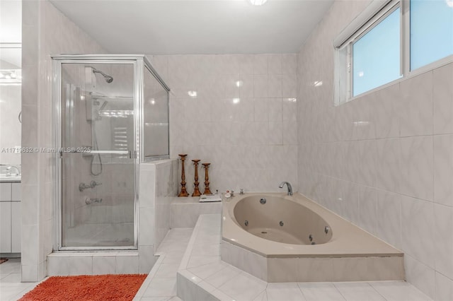 bathroom with tile walls, separate shower and tub, vanity, and tile patterned floors