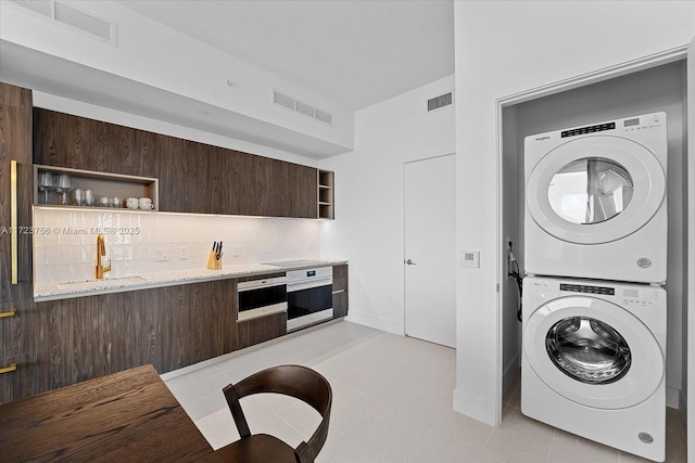 laundry room featuring sink and stacked washer and clothes dryer